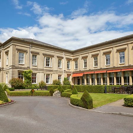 Macdonald Bath Spa Hotel Kültér fotó The photo depicts a large, elegant building with a classic architectural style, featuring a combination of stone and large windows. The structure appears to have two sections: a main, stately part on the left and an adjoining section that has a terra