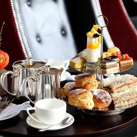 Macdonald Bath Spa Hotel Kültér fotó The photo depicts an elegantly arranged afternoon tea setting. There is a tiered stand filled with a variety of treats, including scones, sandwiches, and small desserts like cakes and pastries. Accompanying this is a teapot and a cup on the table, su