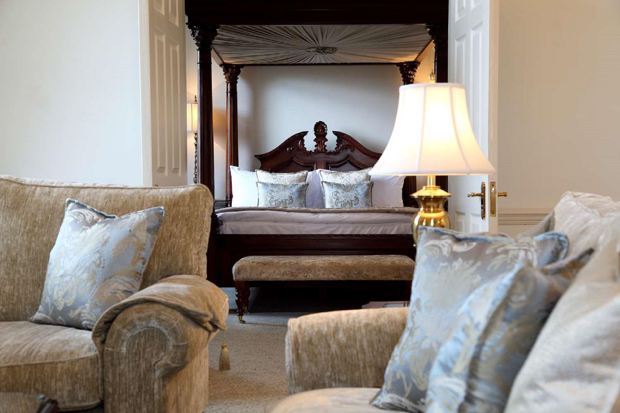 Macdonald Bath Spa Hotel Kültér fotó The photo shows a beautifully decorated room featuring a four-poster bed in the background. The bed has a wooden frame with a rich design, and it is adorned with plush bedding and pillows. In the foreground, there are comfortable sofas with decorativ