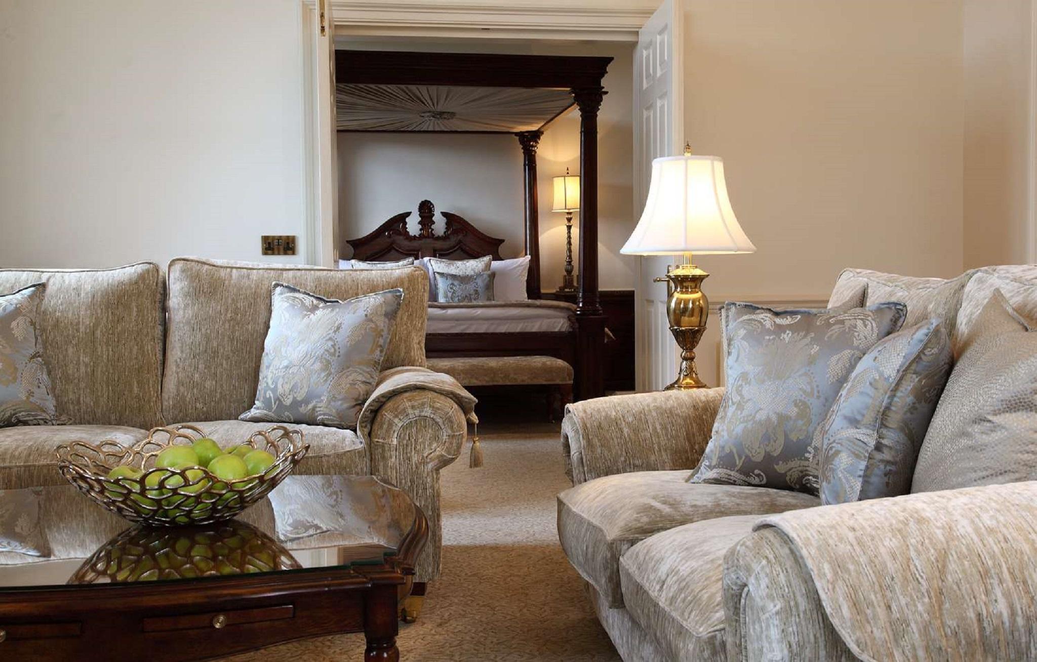 Macdonald Bath Spa Hotel Kültér fotó The photo shows a cozy living space with elegant furnishings. On the left, there is a sofa with plush cushions and a stylish armchair, both in a soft, light-colored fabric. In the center, there is a decorative glass table with a bowl containing what 