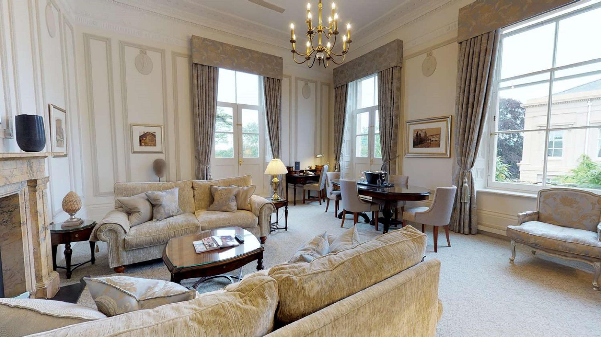Macdonald Bath Spa Hotel Kültér fotó The photo displays a spacious and elegantly furnished living room. It features plush sofas and armchairs arranged around a central coffee table, creating a cozy seating area. Large windows adorned with long curtains allow natural light to fill the ro