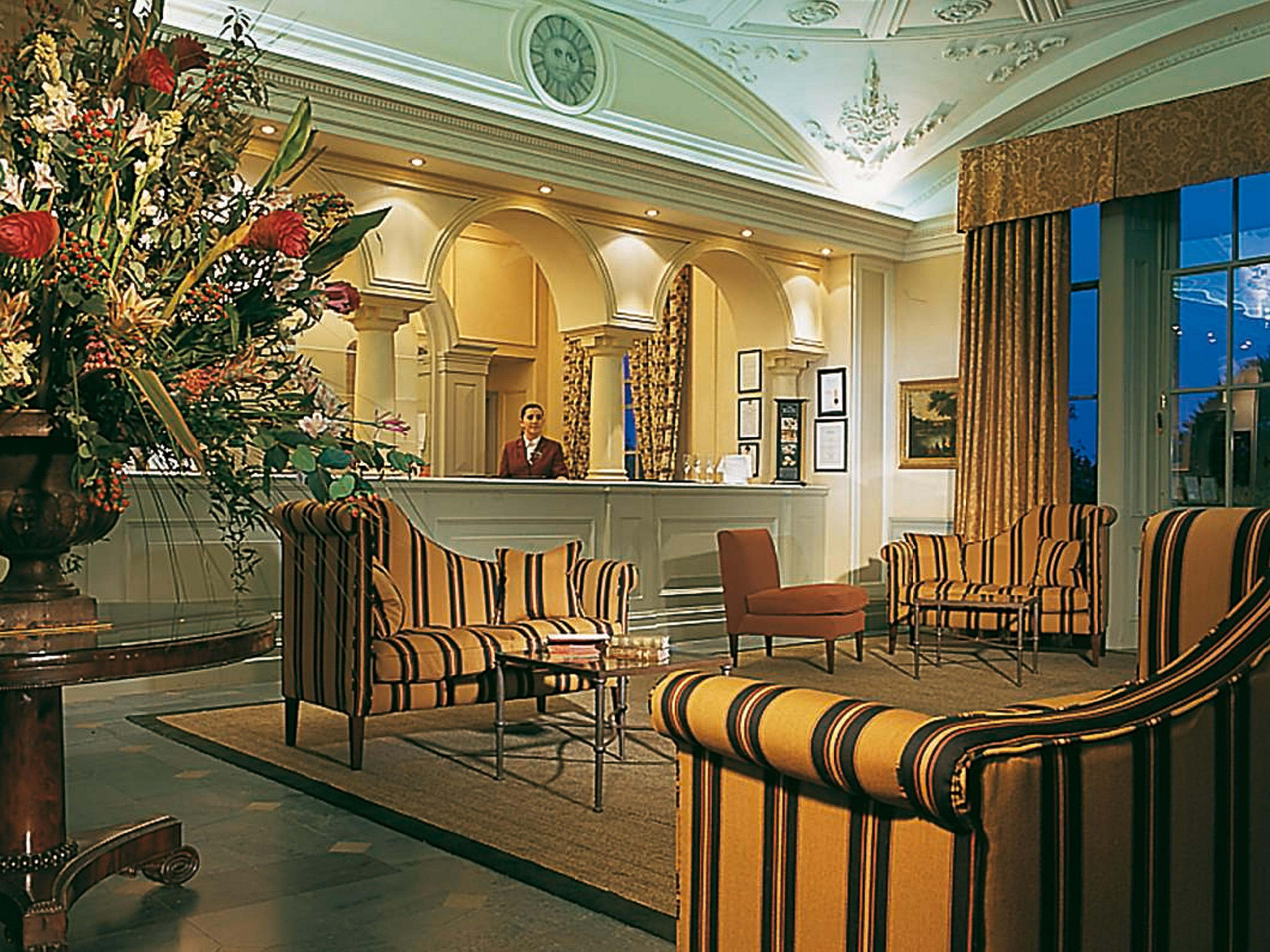 Macdonald Bath Spa Hotel Kültér fotó The photo shows an elegant hotel lobby. The area features a reception desk with a staff member behind it. Surrounding the reception are comfortable seating arrangements, including striped armchairs and a brown chair. A large vase with an elaborate fl