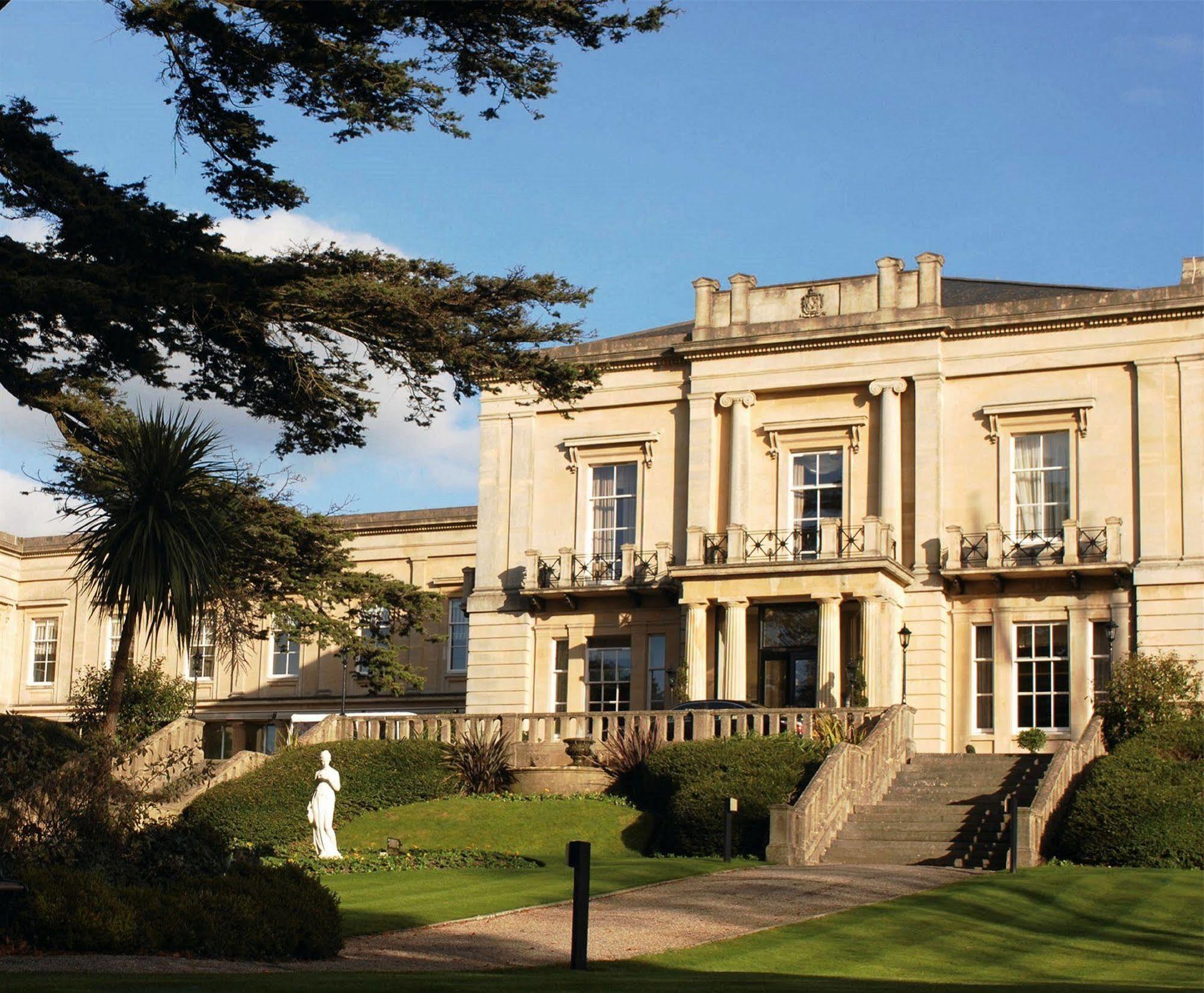 Macdonald Bath Spa Hotel Kültér fotó The photo shows an elegant building with classical architecture, featuring large windows and decorative elements. The facade is light-colored, and there are several balconies. In front of the building, there is a landscaped area with greenery, includ